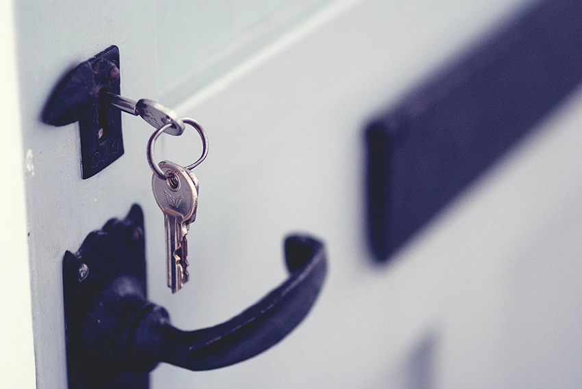 Schlüssel an einem SChlüsselbund steckt im Schloss einer weißen Tür